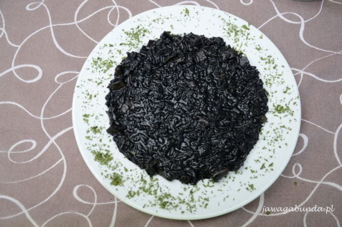 Czarne risotto podane na talerzu. Czarny kolor zawdzięczamy atramentowi z kalmarów..
