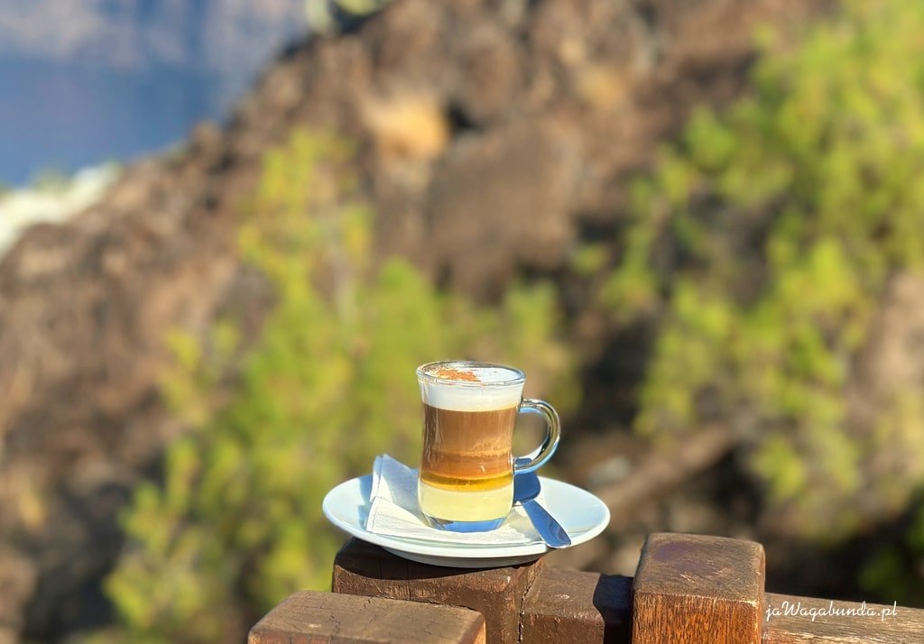 Kawa składająca się z kilku warstw w filiżance na tle gór