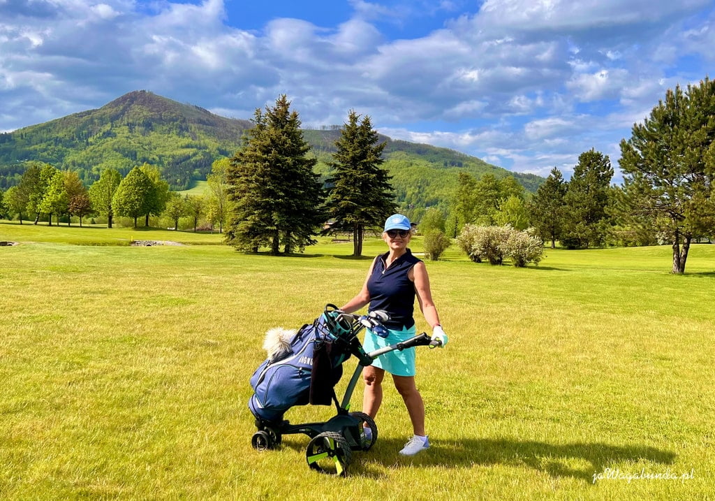 kobieta z wózkiem golfowym na polu golfowym w tle zieleni i gór