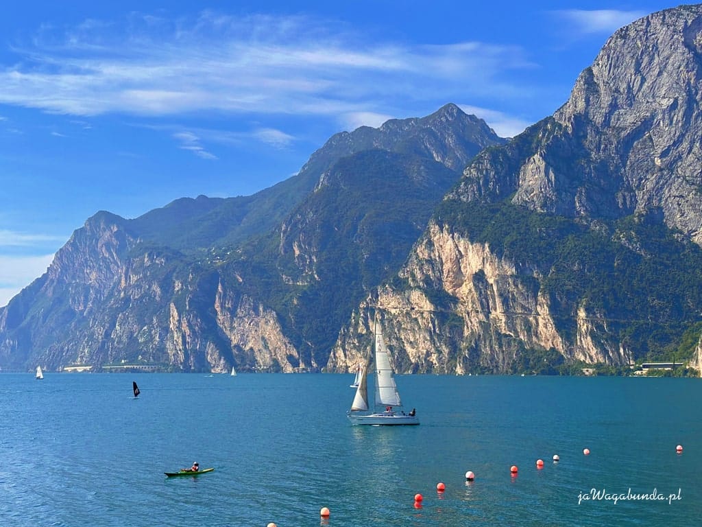 jezioro, na nim żaglówka, strome góry wokół