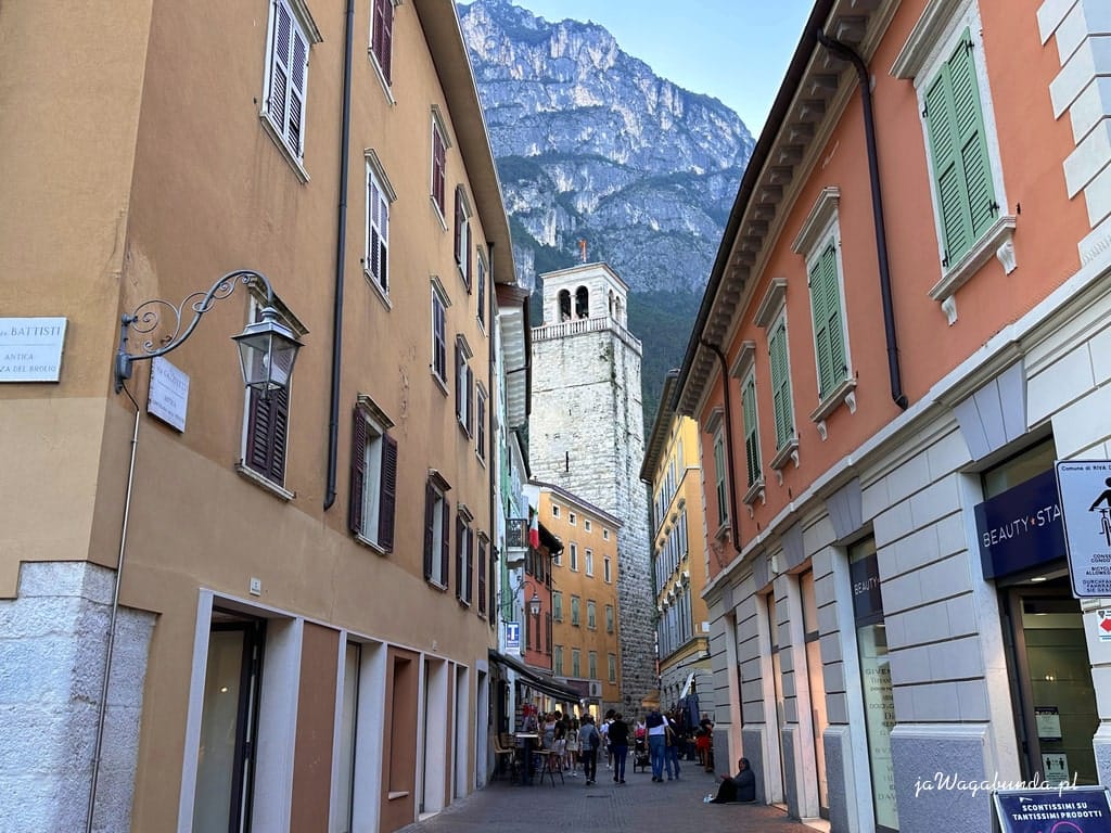 wąska uliczka w starym mieście, na końcu widoczna wieża i wysokie góry